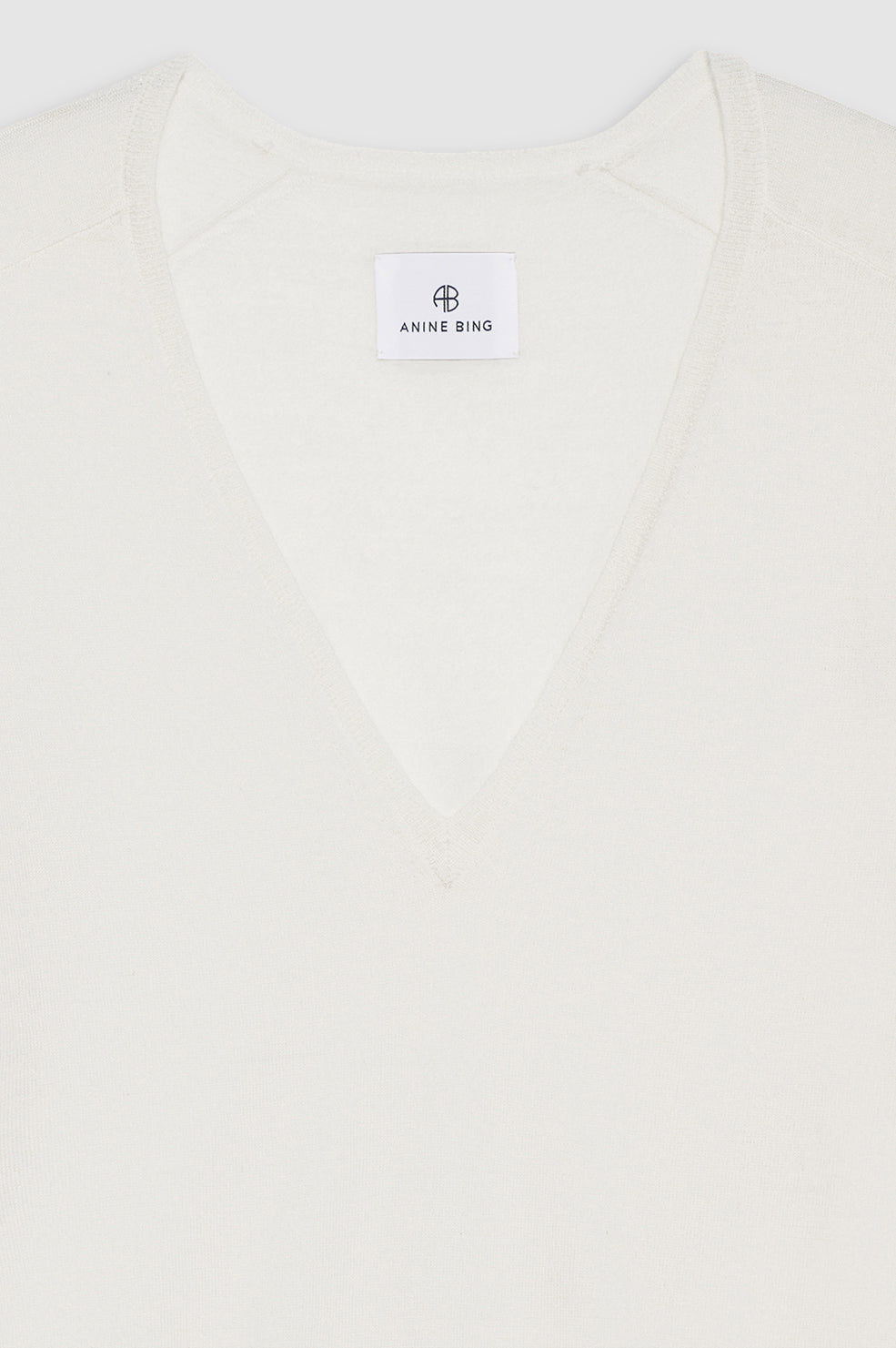 Ivory sweater with a V-neckline and a tag displaying the brand name 