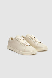 Beige sneakers with a pebbled texture, featuring laces and a low-profile design.