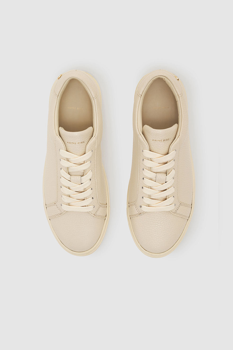 Beige pebbled leather sneakers with round toe and lace-up closure.