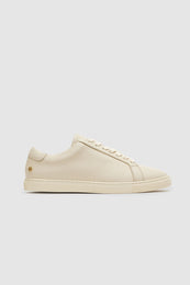 Beige sneakers with a pebbled texture, featuring a lace-up design and a small logo on the heel.