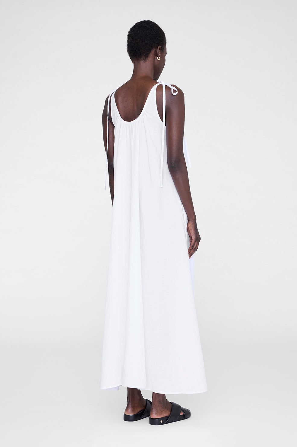 White maxi dress with adjustable straps, featuring a relaxed fit and a flowing silhouette.
