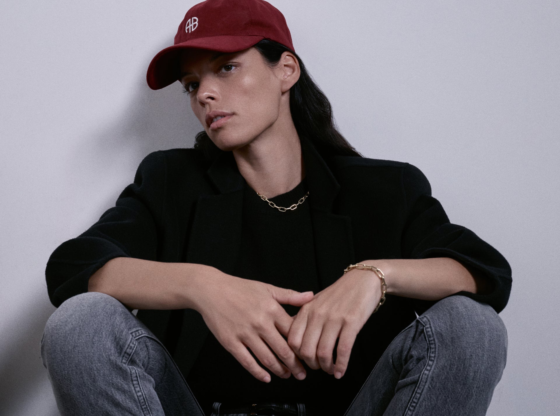 Person wearing a red cap and black jacket sitting against a plain background