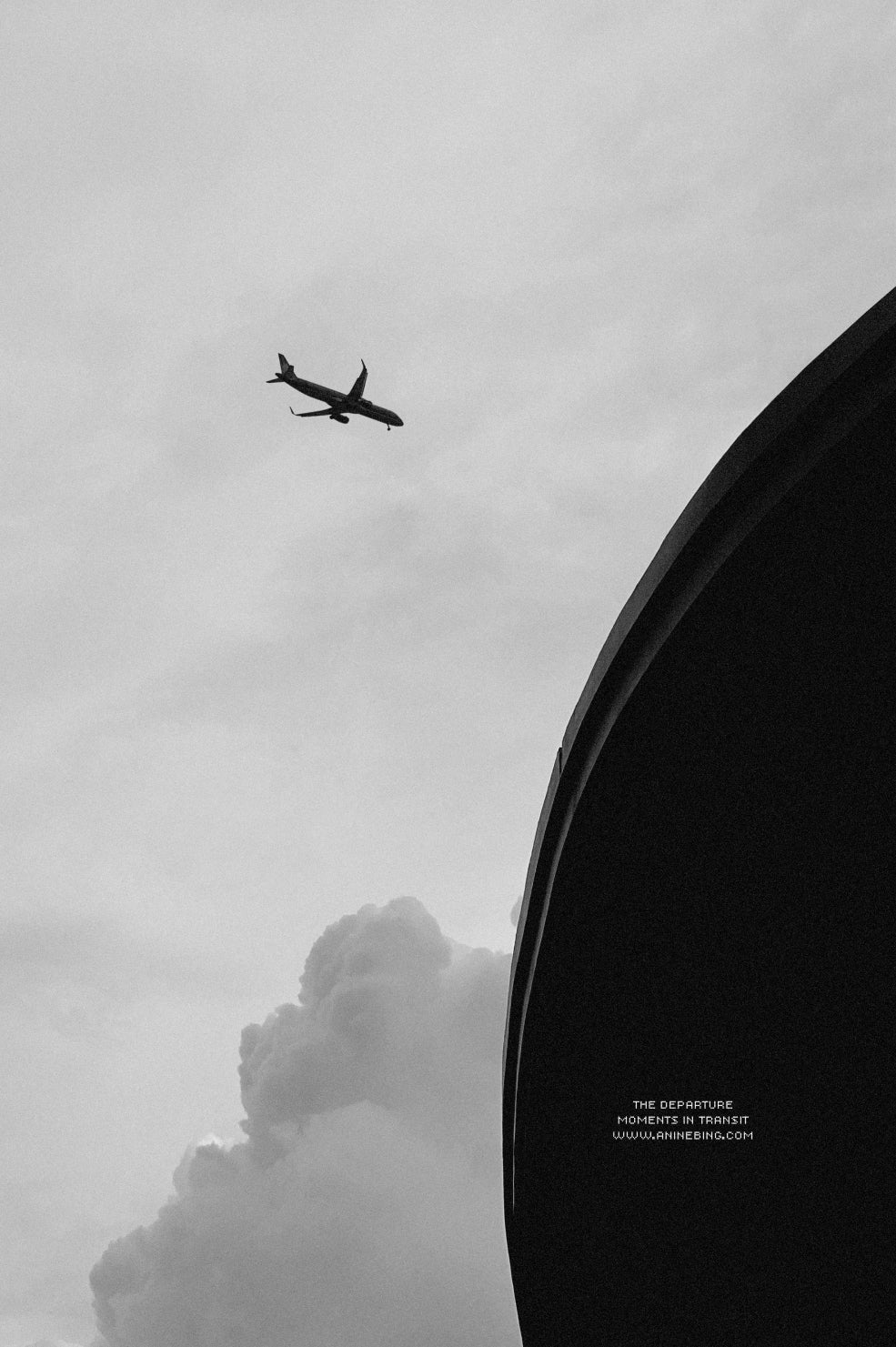 Airplane flying against a cloudy sky with a dark circular object on the right.